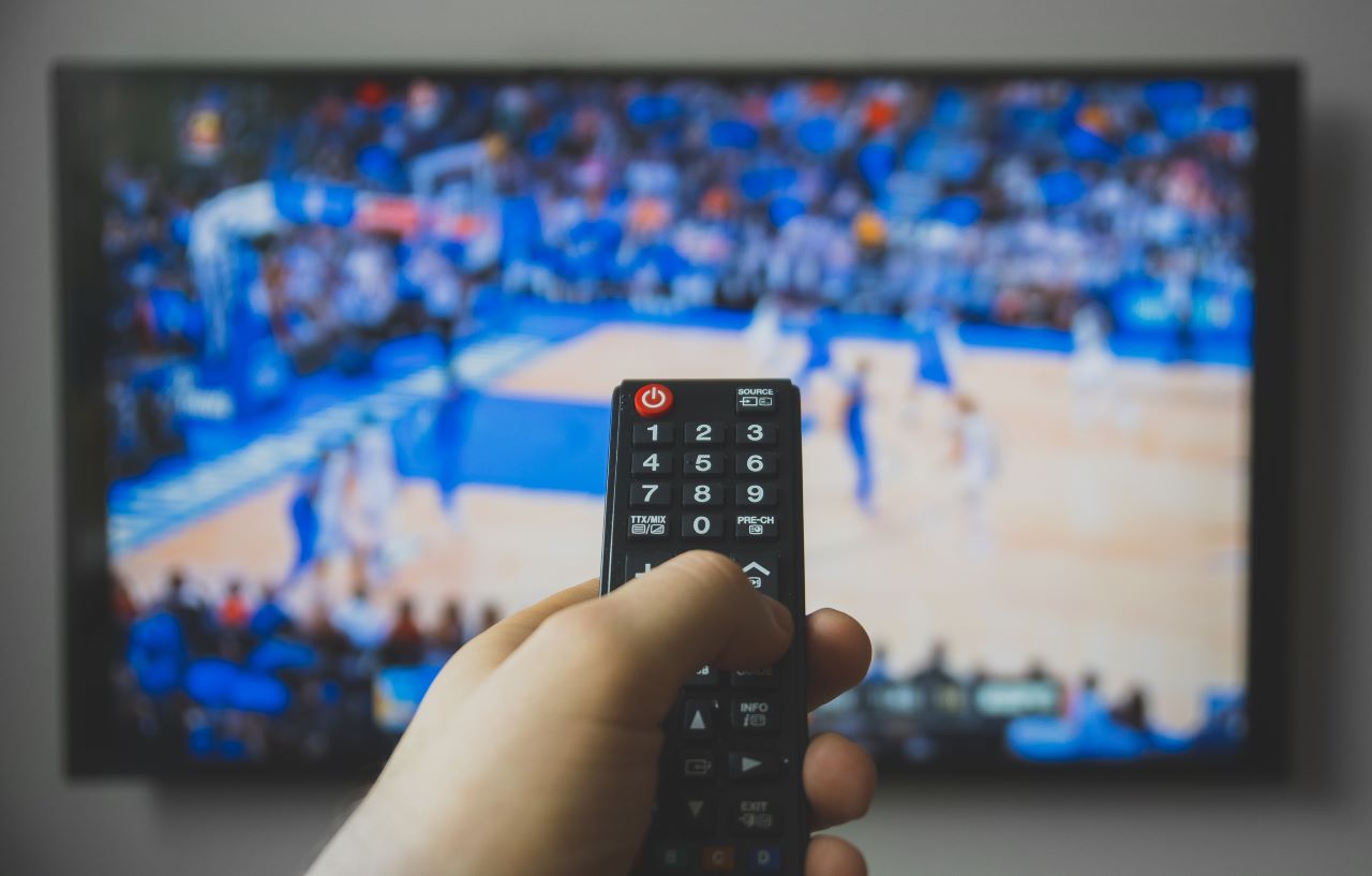 Basketball on TV with hand holding a remote