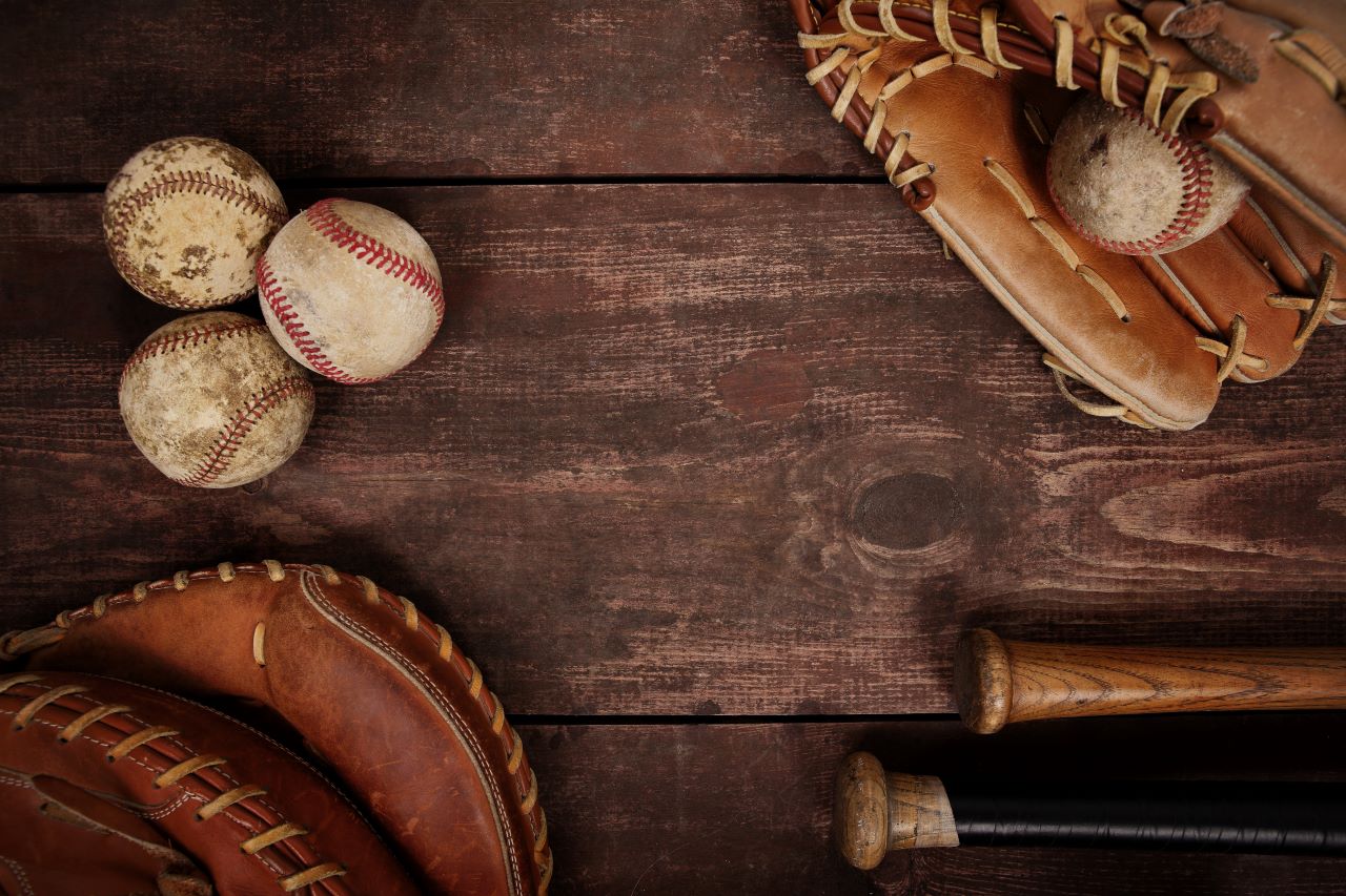 Image of baseballs, gloves and bats on a wooden background