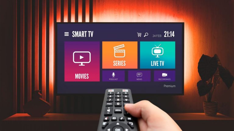 Hand holding remote control pointing at a Smart TV
